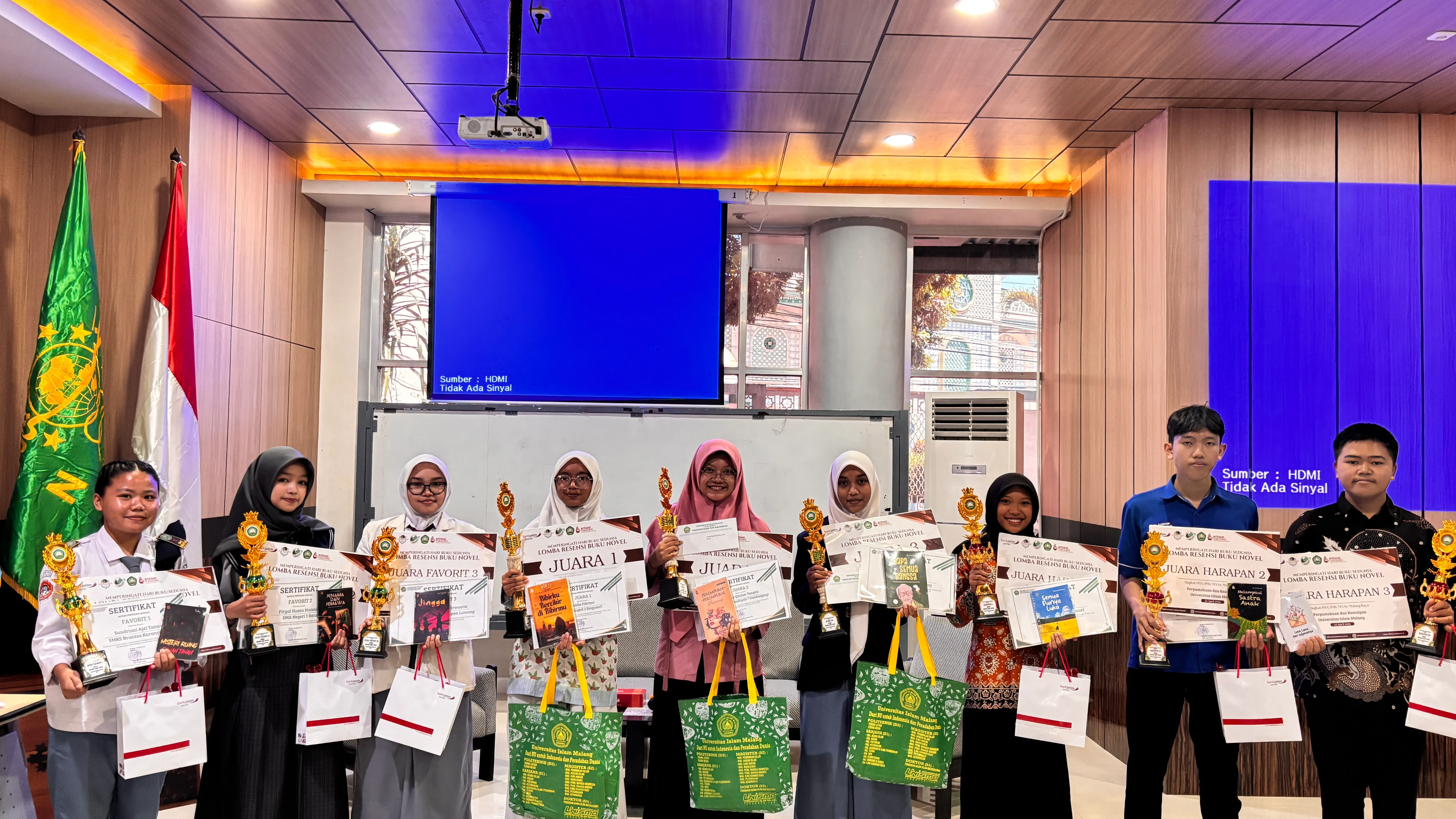 Sembilan pemenang Lomba Resensi Buku Novel Hari Buku Sedunia 2026 memperlihatkan piala dan sertifikat di Ruang Literasi Perpustakaan UNISMA