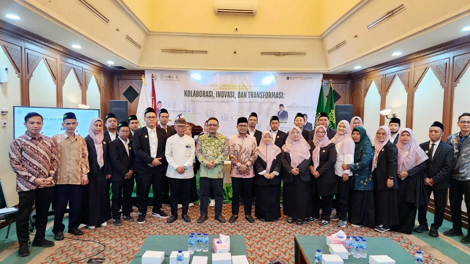 Rombongan pustakawan dan pengurus APPTNU berfoto bersama di depan panggung seminar nasional bertema Kolaborasi, Inovasi, dan Transformasi di Gedung PBNU Jakarta
